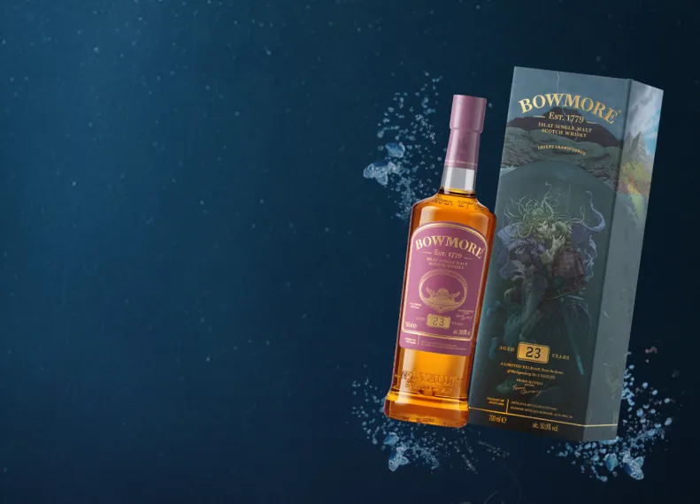 A bottle and outer box tipped at an angle against a blue backdrop showing Frank Quietly 23 Year Old whisky.